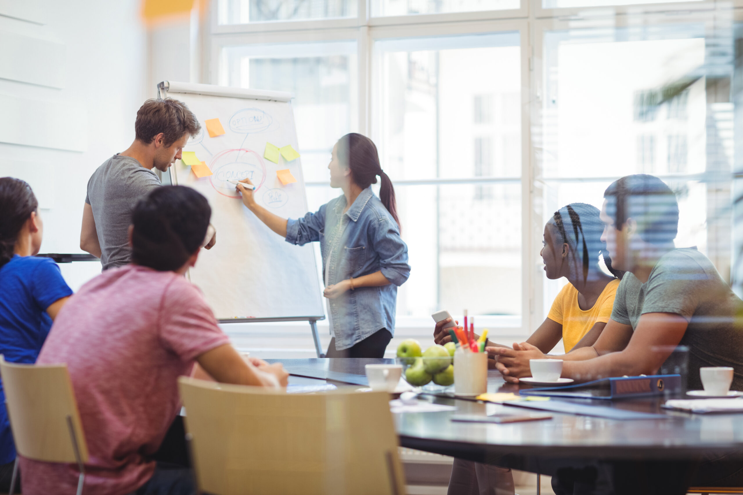 Des cadres d'entreprise discutent avec leurs collègues sur un tableau blanc lors d'une réunion au bureau.