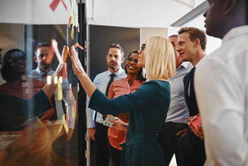 a team brainstorming with sticky notes on a glass wall while working together in a modern office environment
